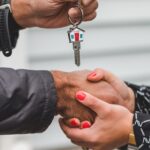 Close-up of a handshake with a house key, symbolizing real estate transactions.